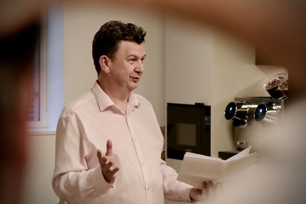 Professor Andy Pardoe delivering a talk on AI in cyber security while gesticulating with his hands